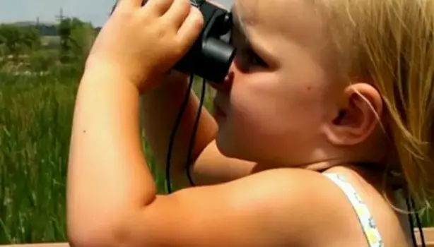 Little Eva at age three looking through binoculars at the world around her.